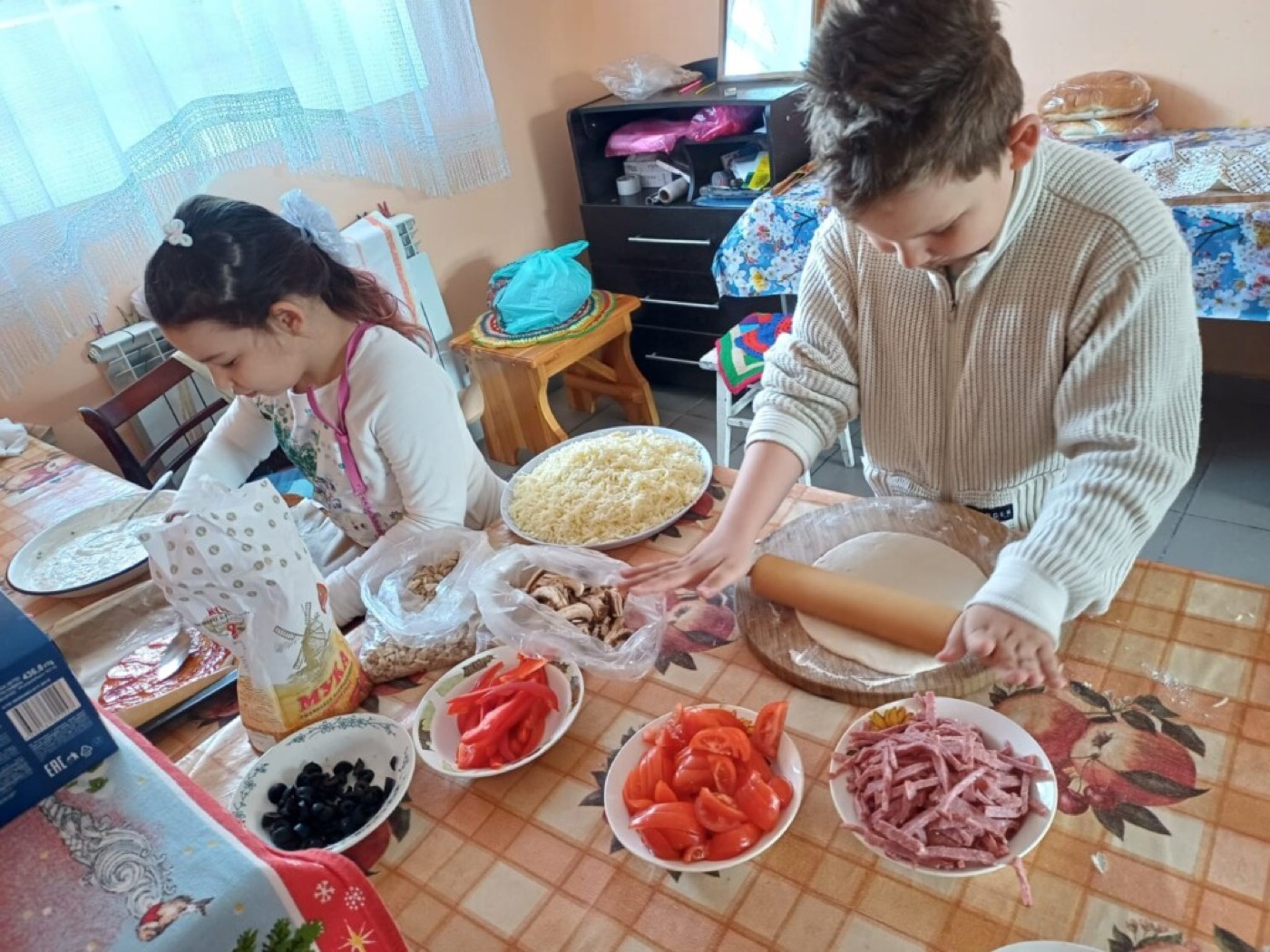 Дети раскатывают тесто под руководством наставника